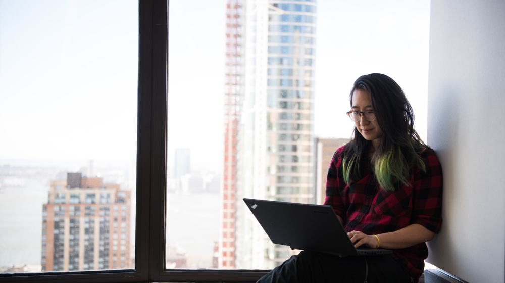 woman on laptop sitting at the window